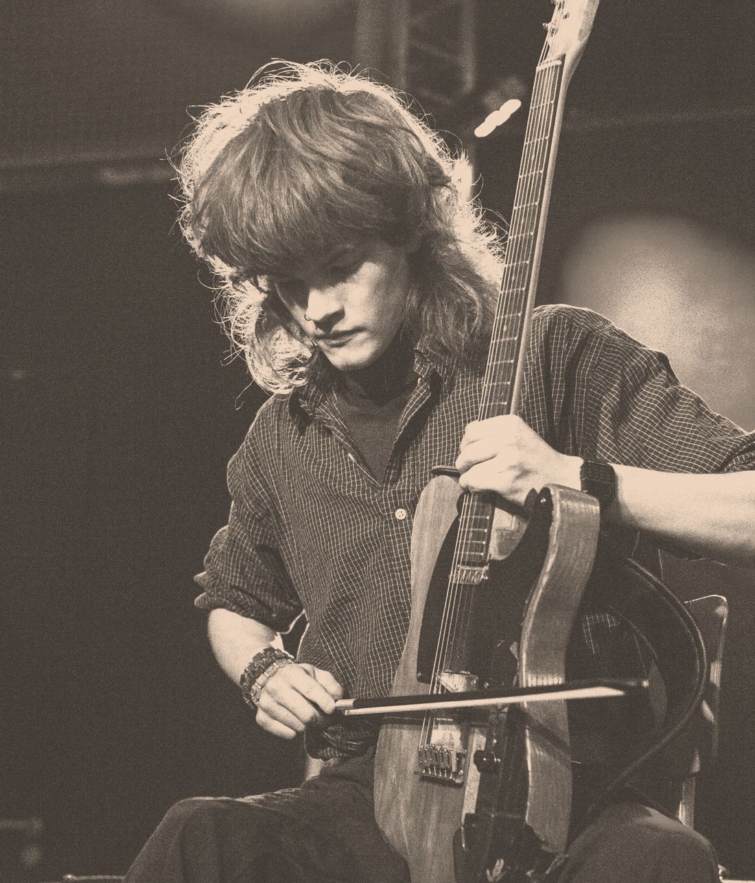 Stijn speelt gitaar met een celloboog op het podium